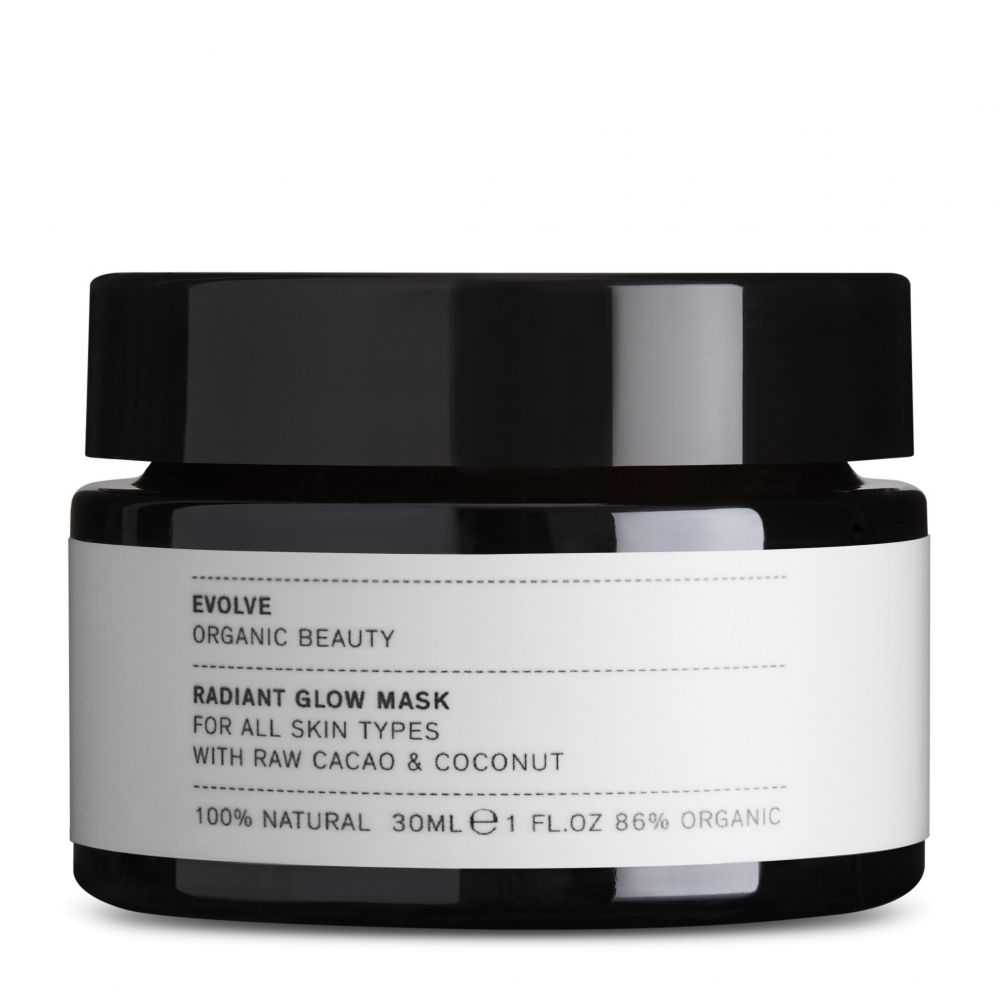 Vaso scuro con coperchio nero. Etichetta con informazioni sul prodotto: EVOLVE, Radiant Glow Mask, per tutti i tipi di pelle, con cacao e cocco.