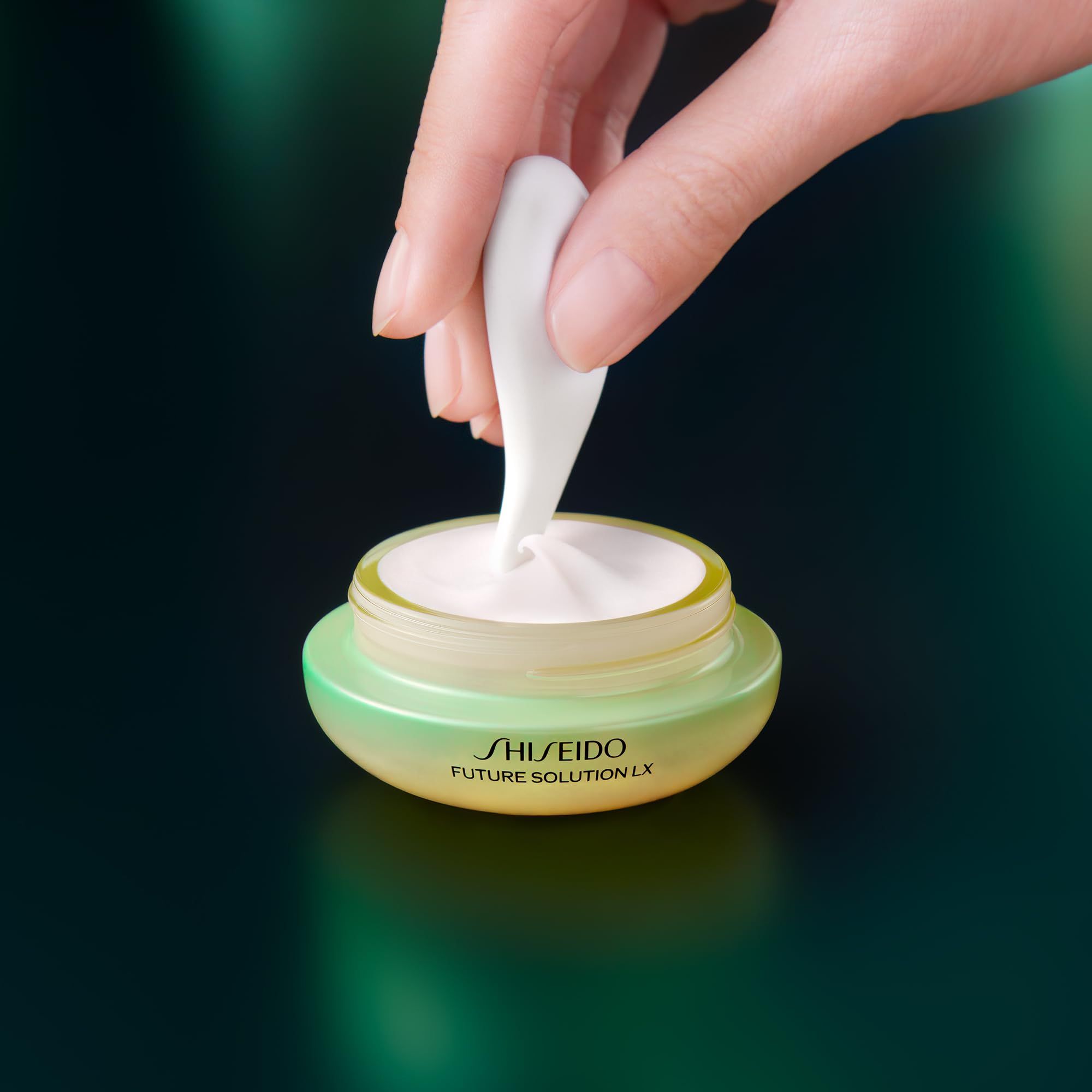 Mano preleva crema con applicatore. Vasetto con scritta: SHISEIDO FUTURE SOLUTION LX.