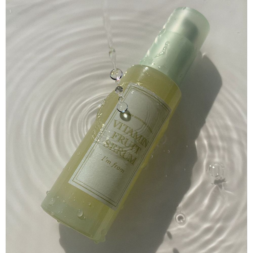 Flacone di siero sott'acqua. Scritta: Vitamin Fruit Serum, I'm from. Gocce d'acqua.