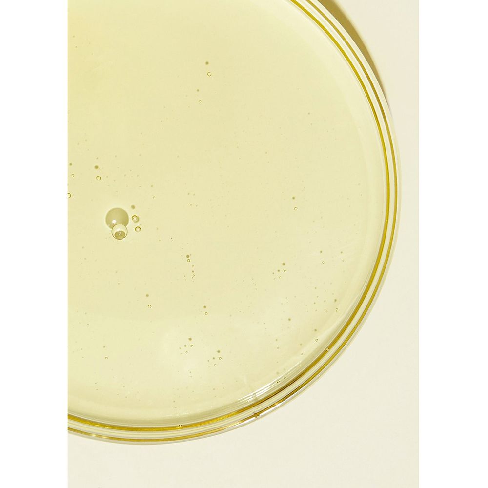 Liquido chiaro e giallastro in una ciotola rotonda e trasparente. Piccole bolle visibili.