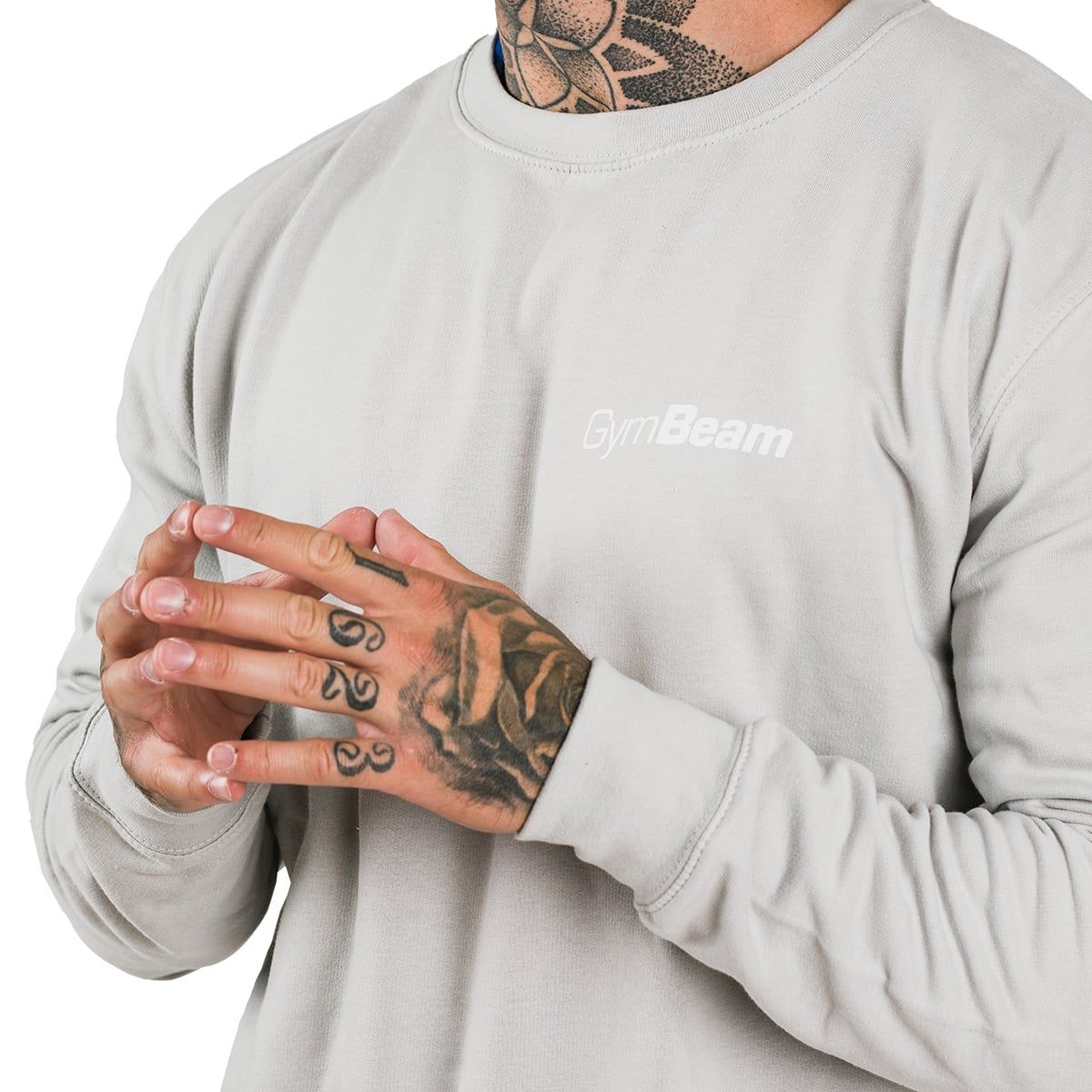 Primo piano delle mani tatuate di un uomo che indossa un maglione grigio.