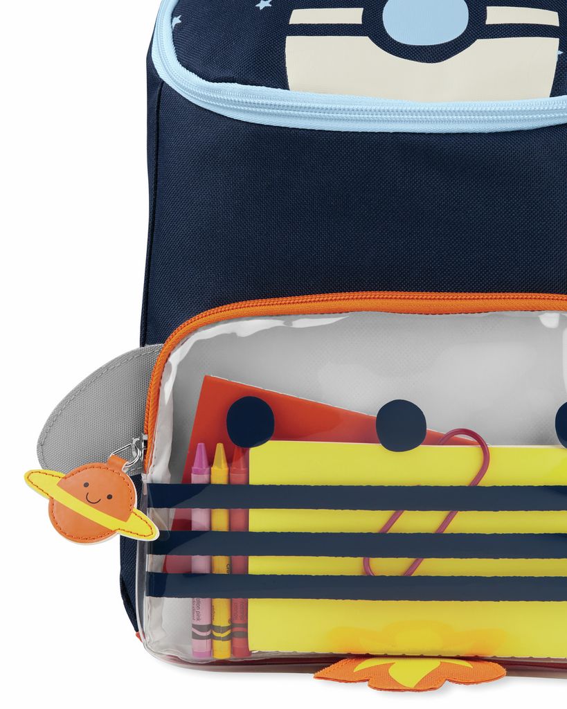 Primo piano dello zaino con scomparto trasparente. Contiene matite e carta. Il logo Skip Hop è visibile.