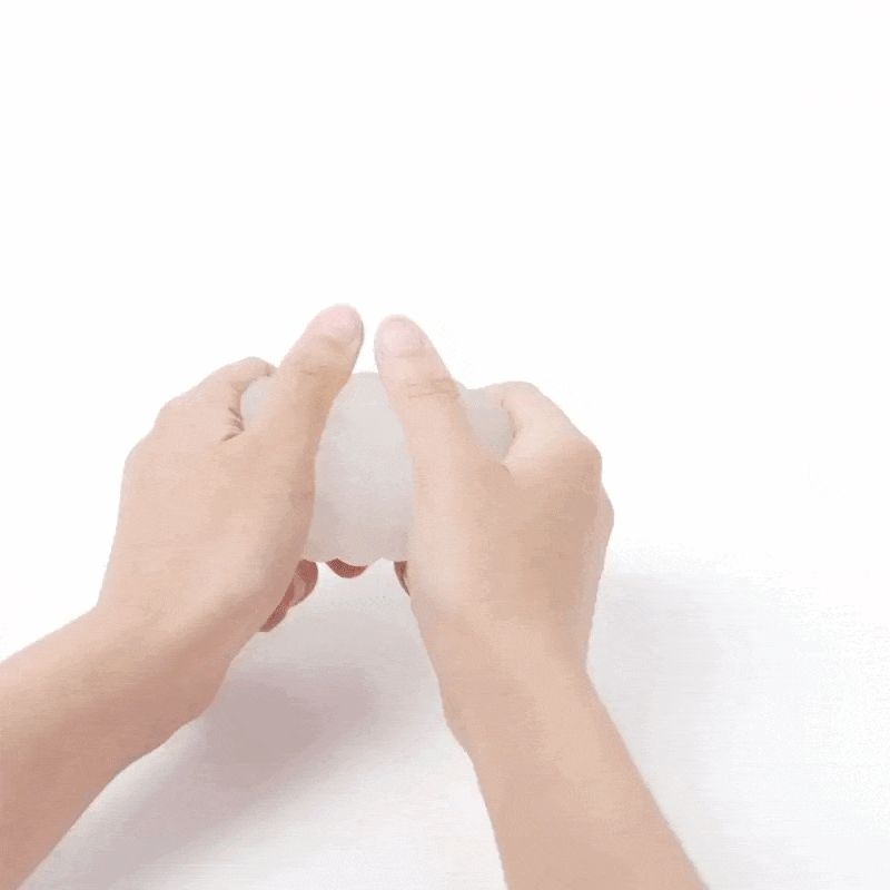 Mani che tengono un oggetto bianco ondulato. Sfondo bianco.