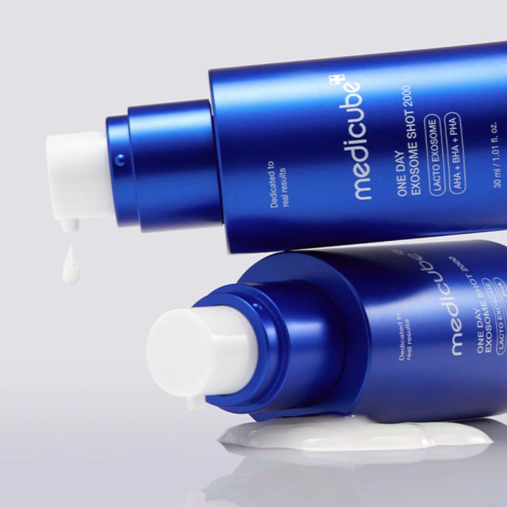 Due flaconi blu, liquido del prodotto che gocciola. Nome e marchio visibili.