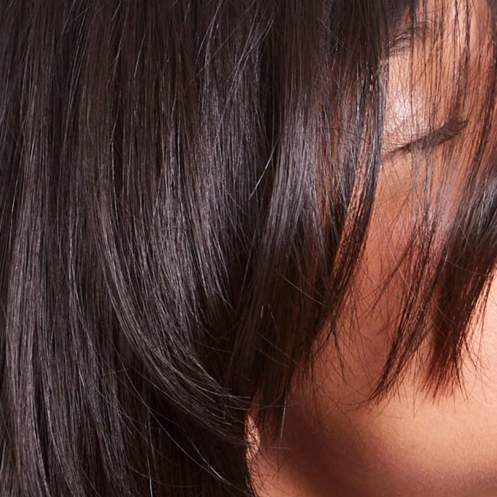 Primo piano di una persona con capelli scuri. I capelli coprono parte del viso.