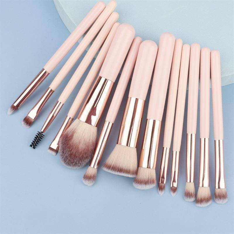 Set di pennelli per trucco. Manici rosa, ghiera dorata, diverse testine. Su sfondo blu.