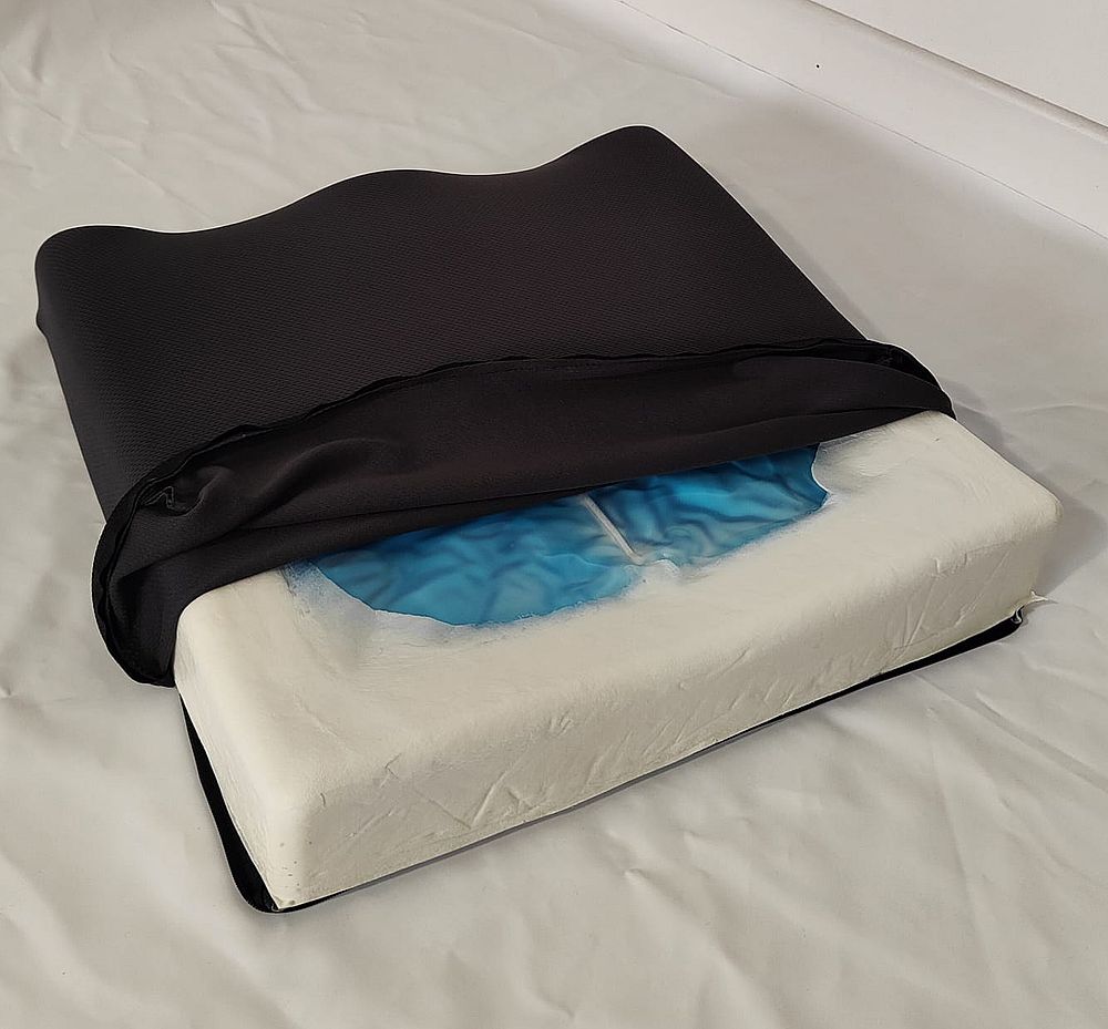 Cuscino rettangolare con rivestimento in tessuto nero. Base in schiuma beige con inserto in gel blu. Forma ergonomica.