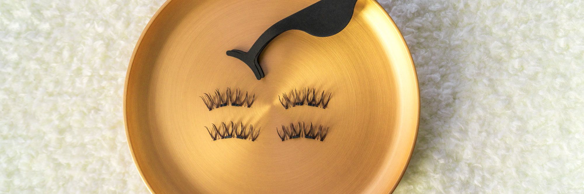 Applicatore per ciglia e ciglia su superficie dorata. Logo: K.