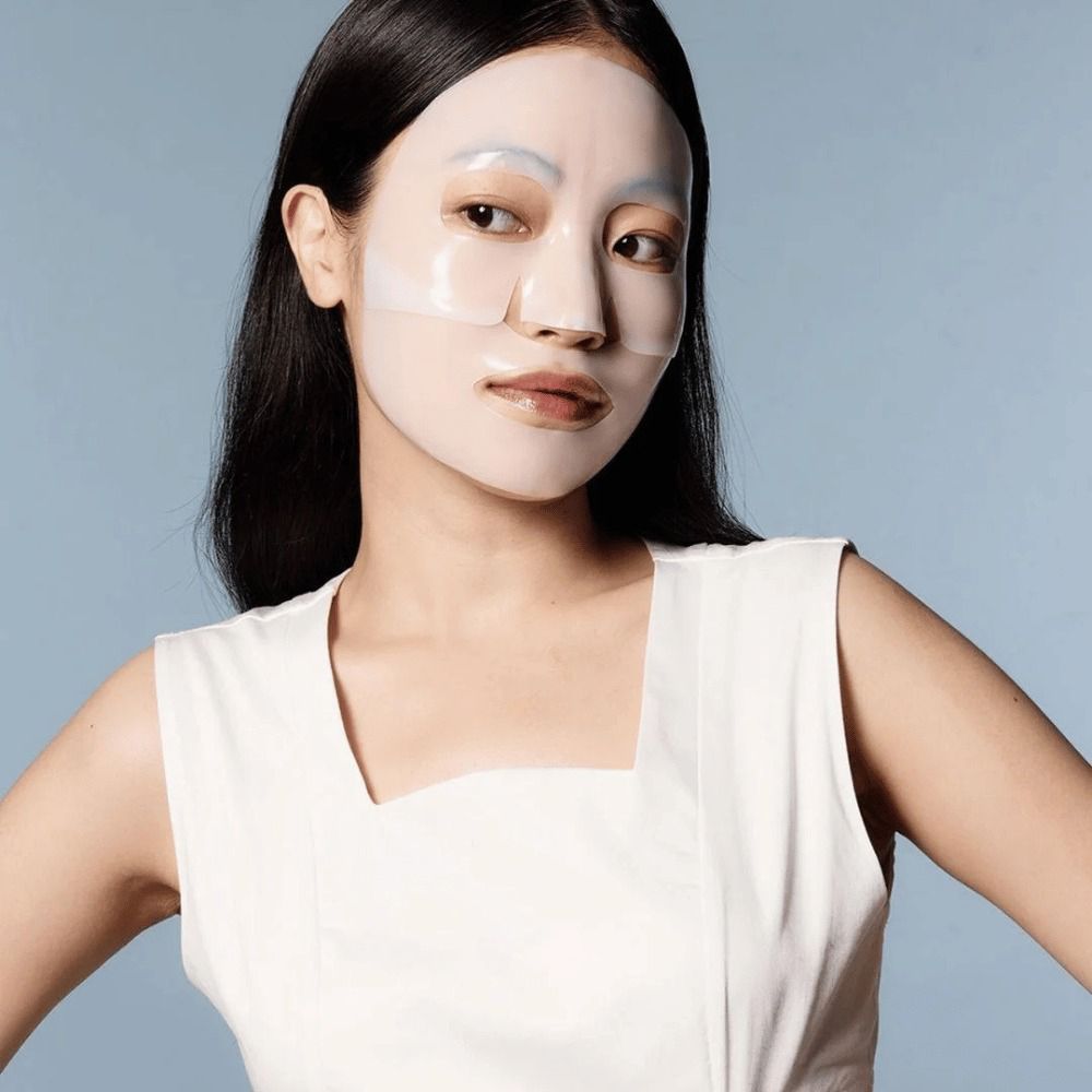 Donna con maschera per il viso. Sfondo blu. Maschera trasparente che copre il viso.
