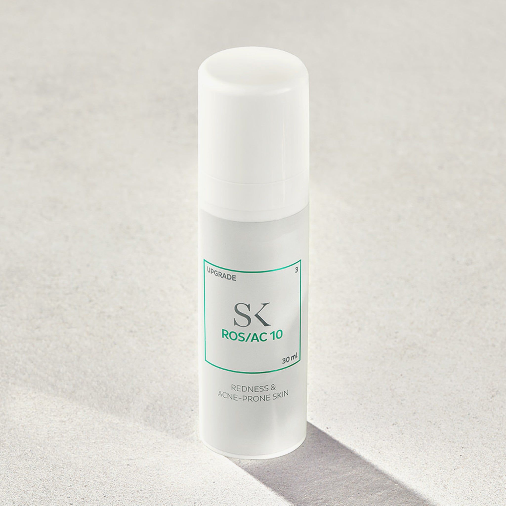 Flacone bianco con etichetta verde. Scritta: SK ROS/AC 10, 30 ml. Testo: Redness & Acne-Prone Skin. Ombra.