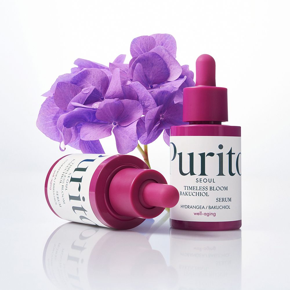 Due flaconi di siero viola con contagocce e fiori viola. Scritta: Purito Timeless Bloom Bakuchiol Serum.