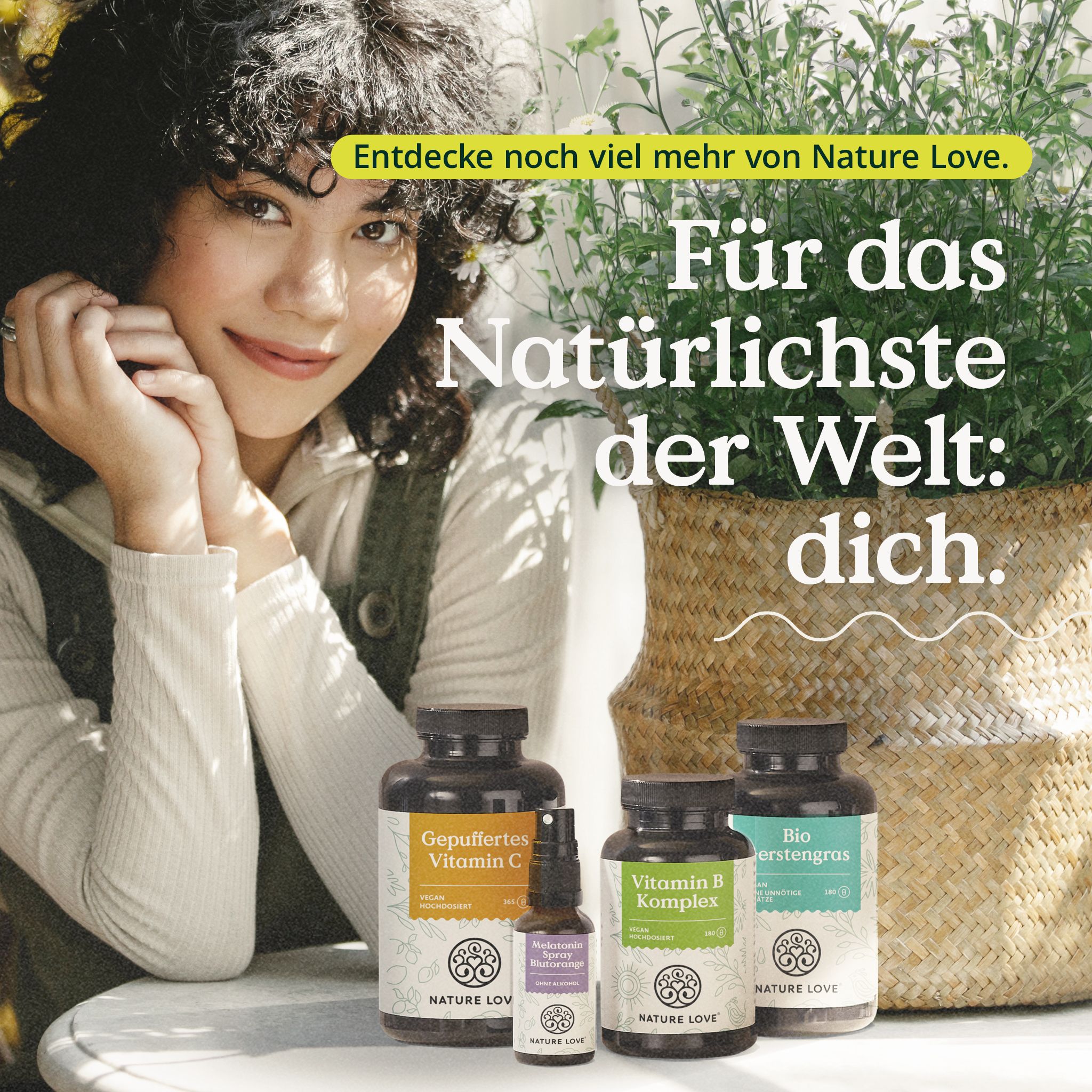 Donna sorridente. Diverse bottiglie di integratori alimentari. Marchio: NATURE LOVE®. Prodotti: Vitamina C, Complesso di vitamina B, Bio Erstengross.