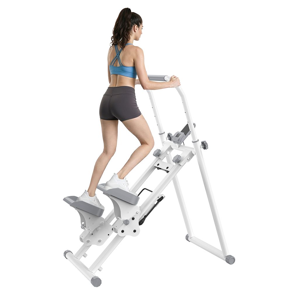 Una donna si allena su uno stepper bianco con manubrio e pedali. Lo stepper ha un display.