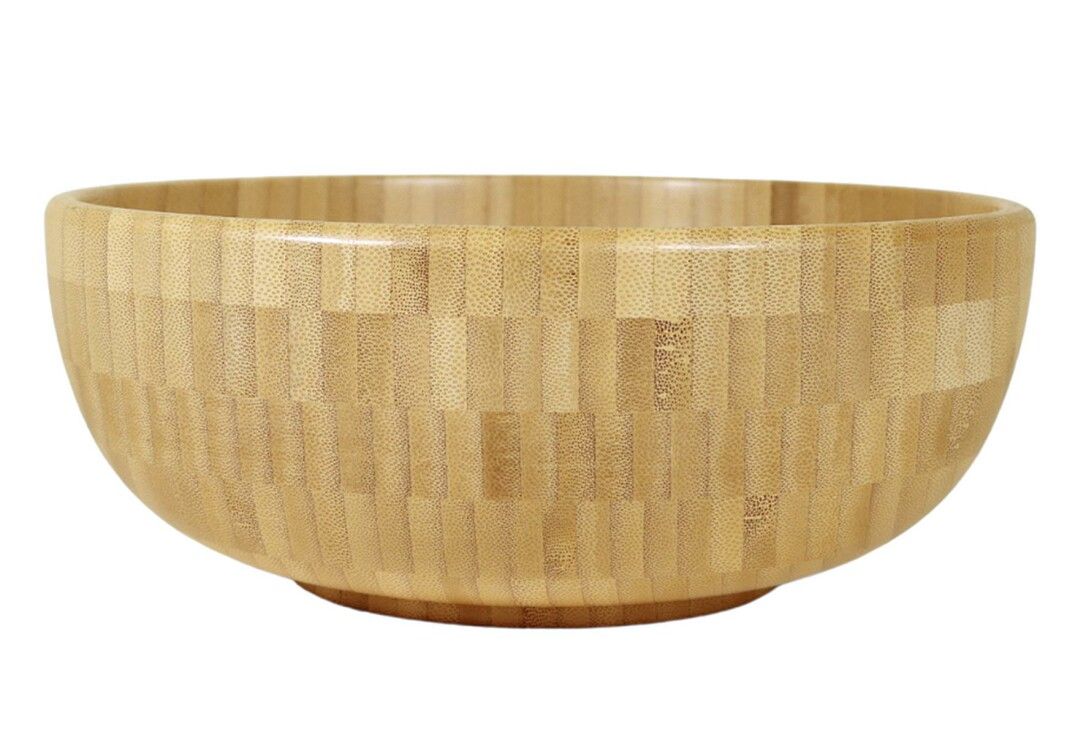 Ciotola rotonda in legno chiaro. La superficie è composta da piccoli pezzi di legno. La ciotola ha una forma arrotondata.