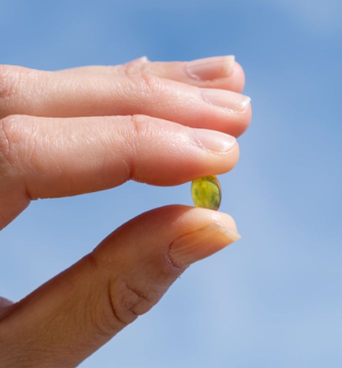 Dito che tiene una capsula molle di Aavalabs Vitamina D3.