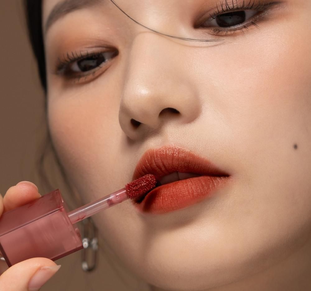 Primo piano di una donna che applica il lucidalabbra con un applicatore. Le labbra sono coperte di lucidalabbra.