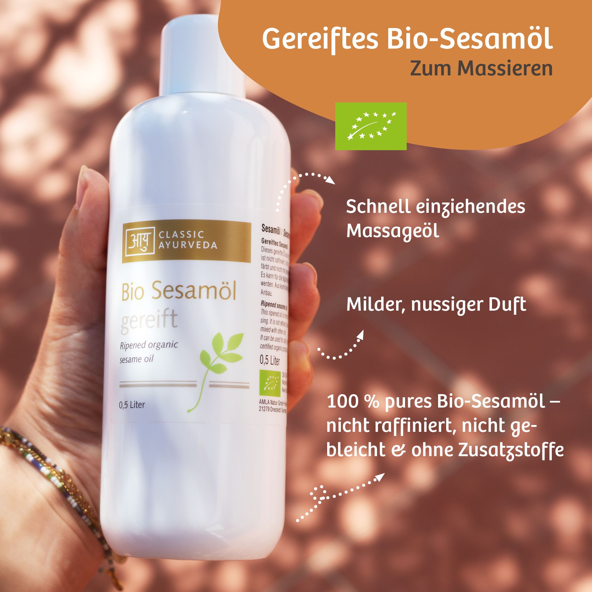 Flacone bianco con etichetta. Scritta: Classic Ayurveda Bio Sesamöl gereift. 0,5 litri. Sigillo biologico. Mano che tiene il flacone.