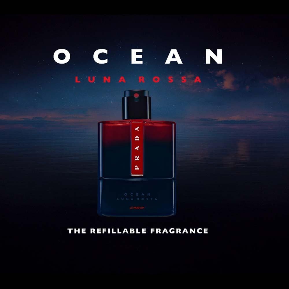 Flacone su sfondo marino. Flacone: blu scuro, rosso, logo Prada. Testo: OCEAN LUNA ROSSA, THE REFILLABLE FRAGRANCE.