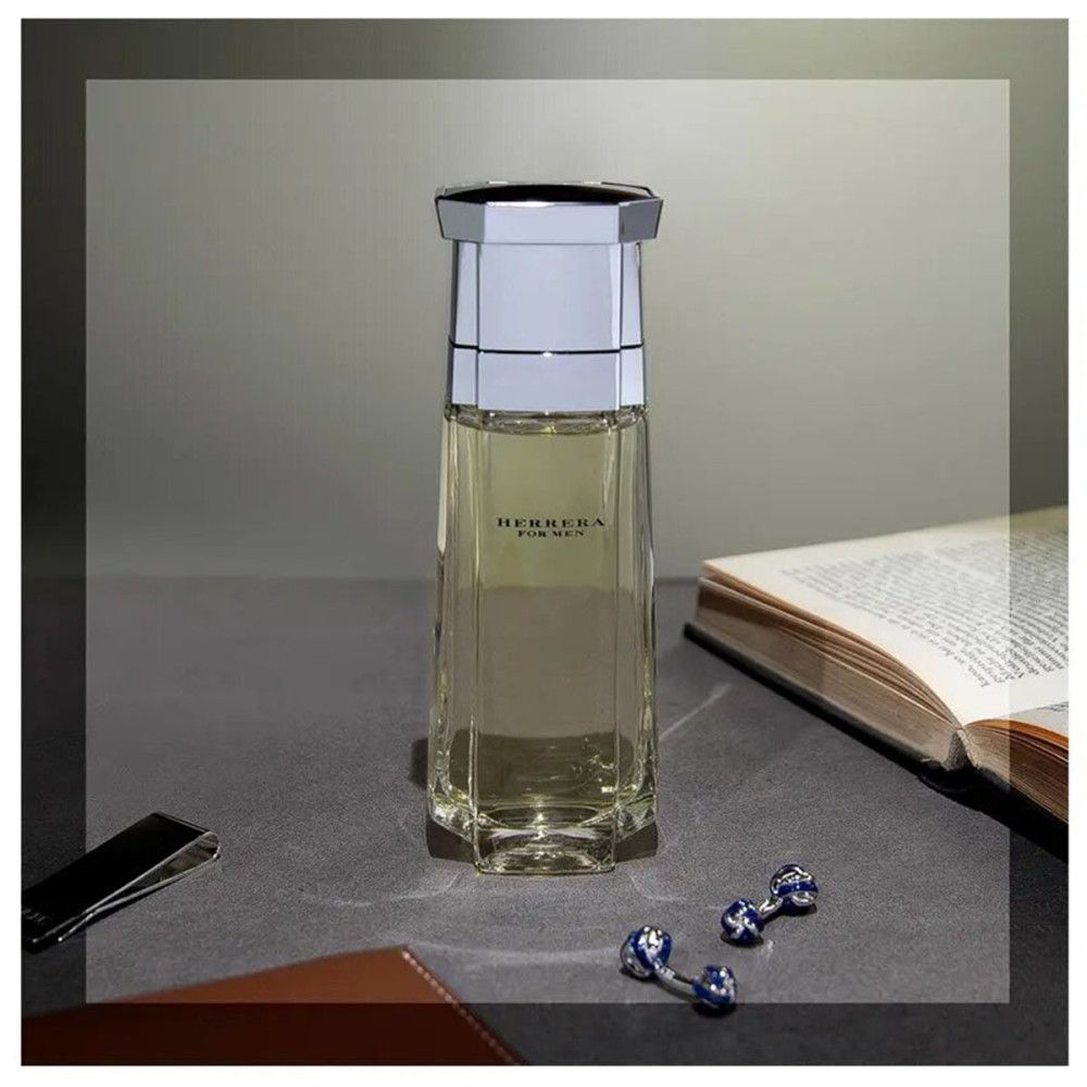 Flacone in vetro con tappo argentato, accanto a libro, gemelli e fermasoldi su un tavolo.