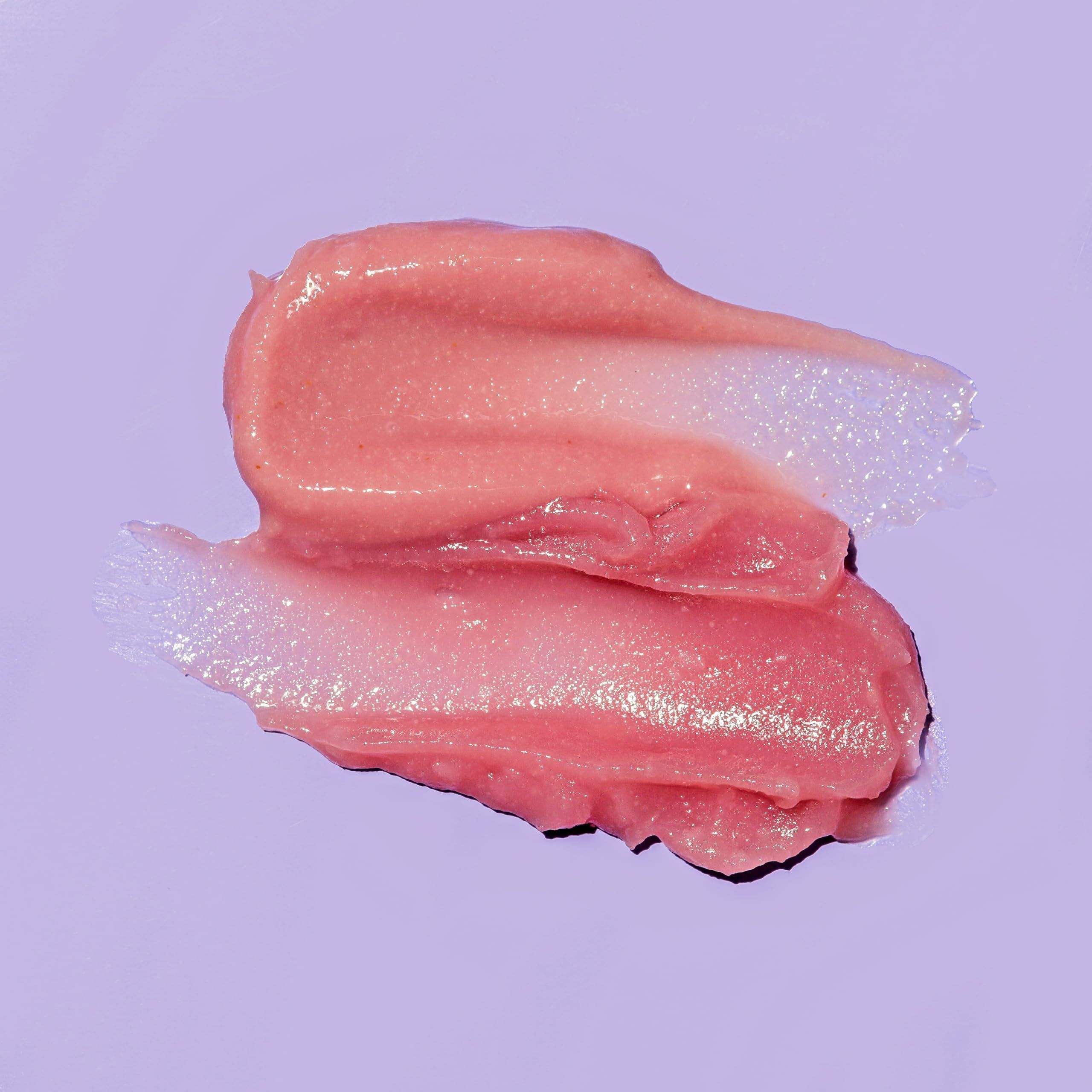 Due strisce rosa di scrub labbra su sfondo viola. La consistenza è riconoscibile.