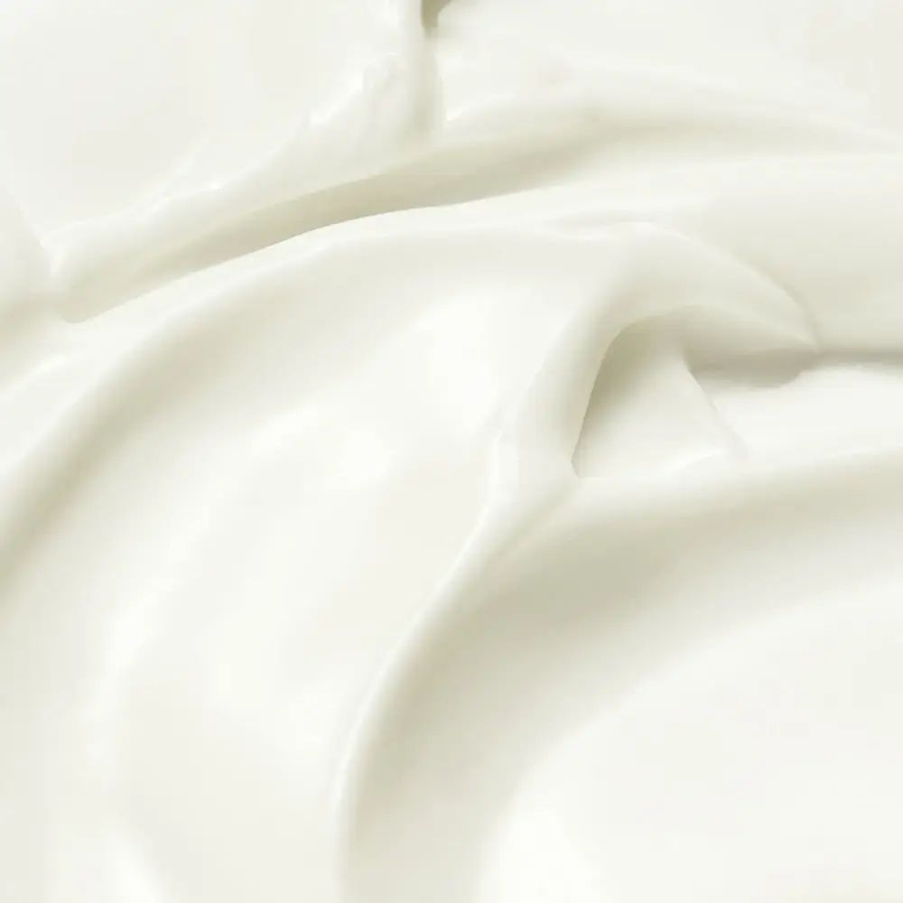 Primo piano di crema bianca. Texture liscia con dolci onde e riflessi.