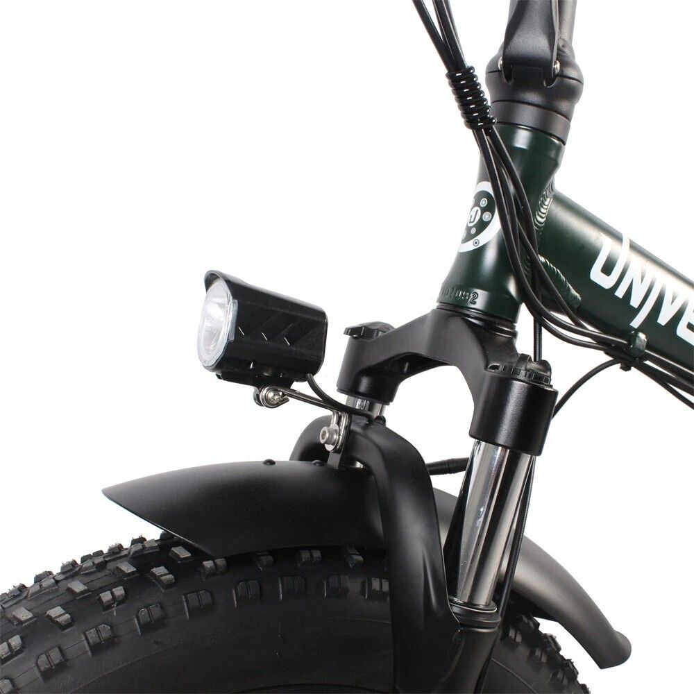 Primo piano della forcella anteriore di una e-bike. Faro, parafango, pneumatico largo.