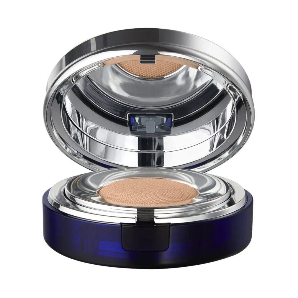 Fondotinta compatto aperto. Contenitore blu, coperchio argentato. Spugna e specchio visibili. Tonalità beige.