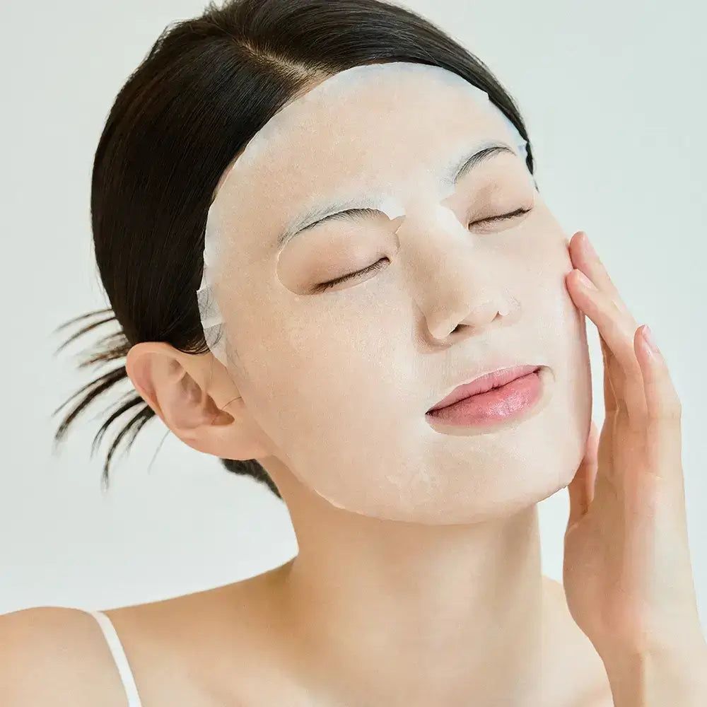 Viso di donna con maschera. La maschera copre la pelle. Una mano tocca la guancia.