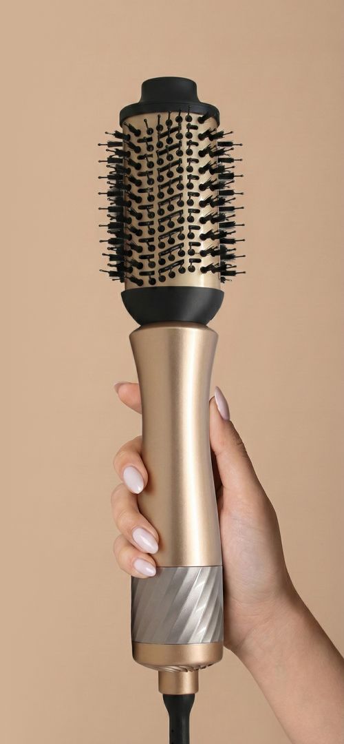 Spazzola styler dorata con spazzola rotonda nera e setole, tenuta da una mano.