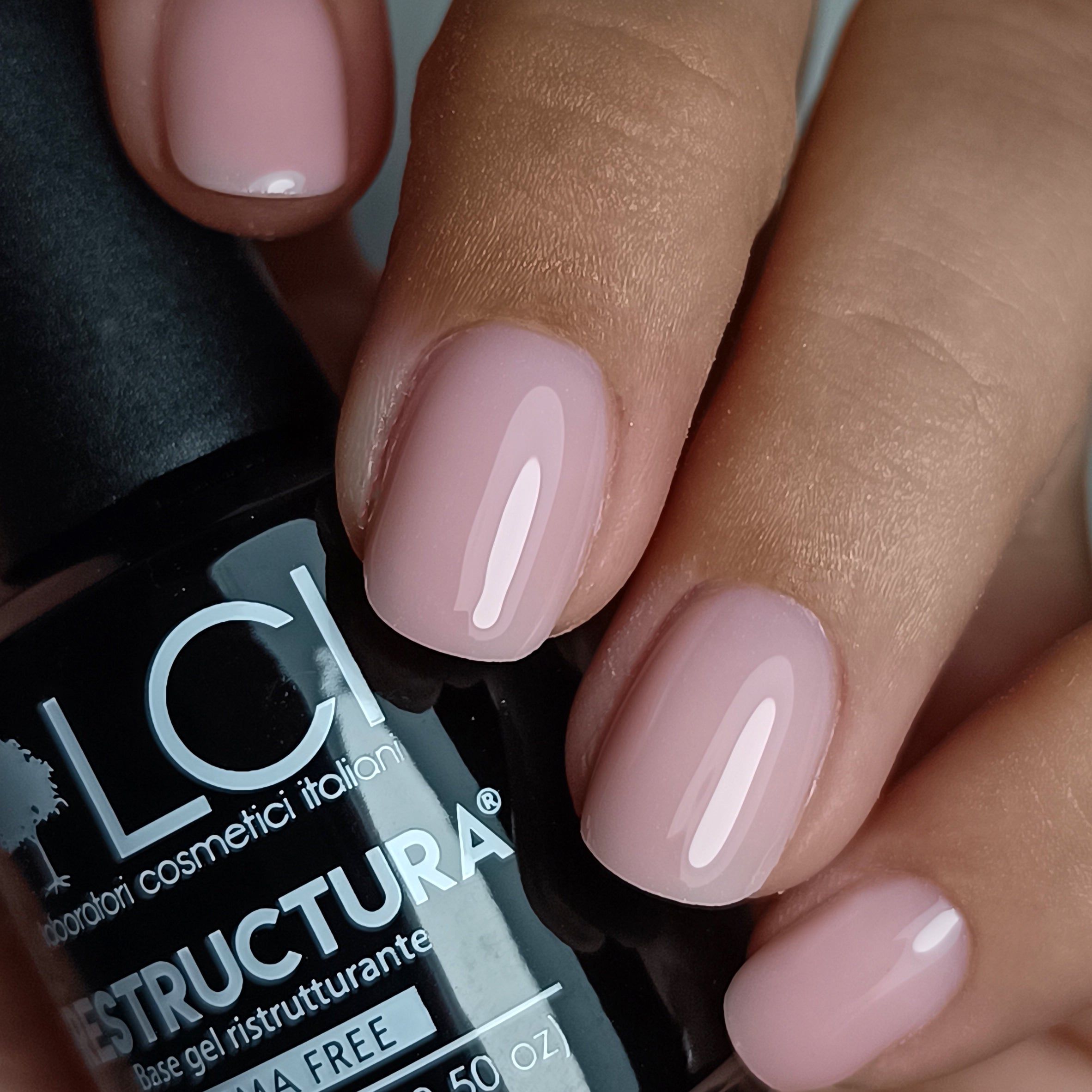 Mano con unghie smaltate di rosa. Accanto, flacone nero con scritta: LCI, Restructura, Hema Free.