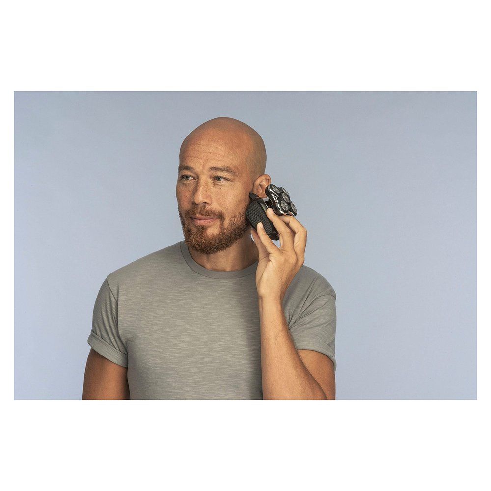 Uomo calvo si rade la tempia con il rasoio Remington XR 1500.