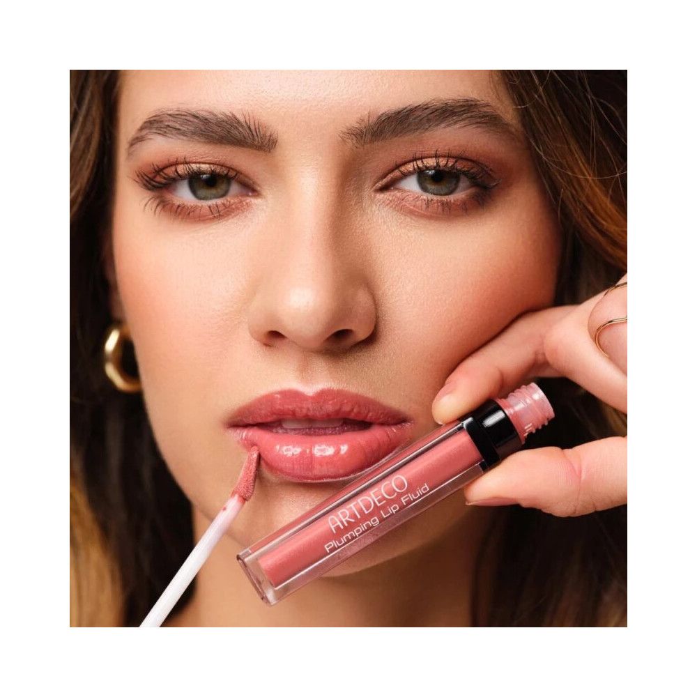 Donna applica Artdeco Plumping Lip Fluid 028 Goddess. Prodotto e applicatore visibili. Rossetto rosa.