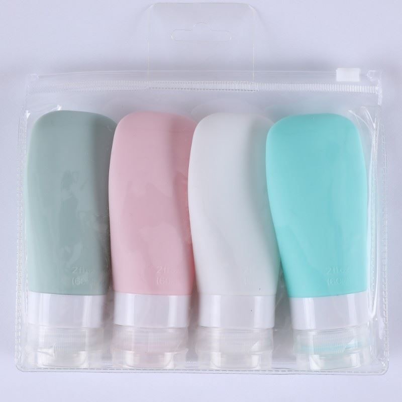 Quattro flaconi da viaggio colorati in una borsa trasparente. Colori: verde, rosa, bianco e turchese. Con coperchio bianco.