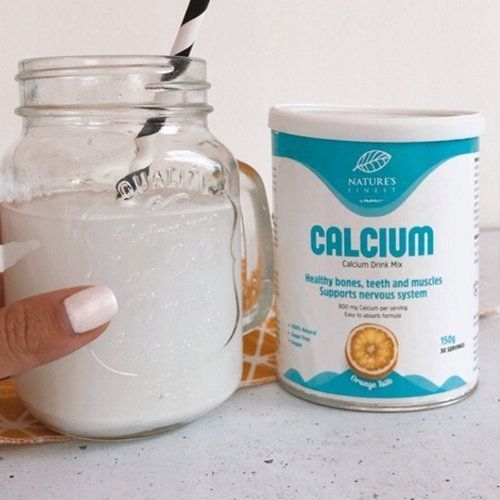 Barattolo Nature's Finest Calcium accanto a un bicchiere di bevanda al calcio con cannuccia.
