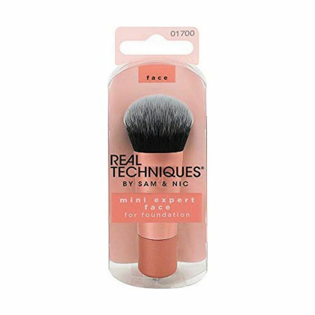 Mini Expert Face Brush in confezione. Manico rosa, setole nere e grigie. Testo: Real Techniques.
