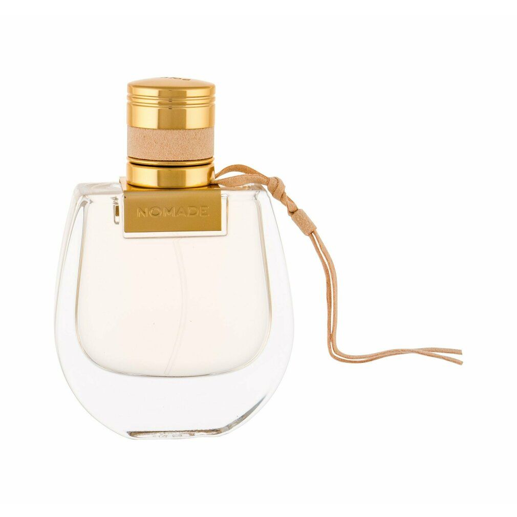 Flacone di profumo con tappo dorato e scritta "NOMADE". Cinturino in pelle beige. Contenitore in vetro trasparente.