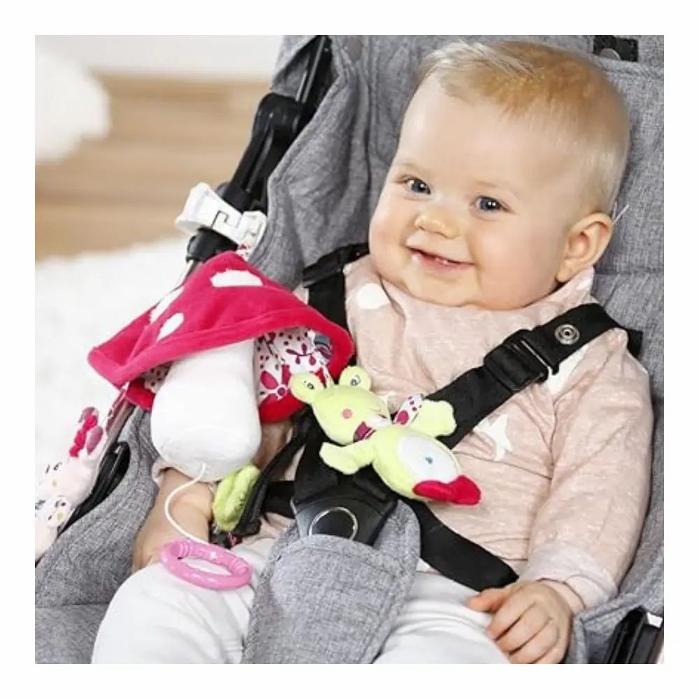 Bambino in passeggino con mobile. Mobile con fungo, cerbiatto e rana. Bambino seduto nel passeggino e sorridente.