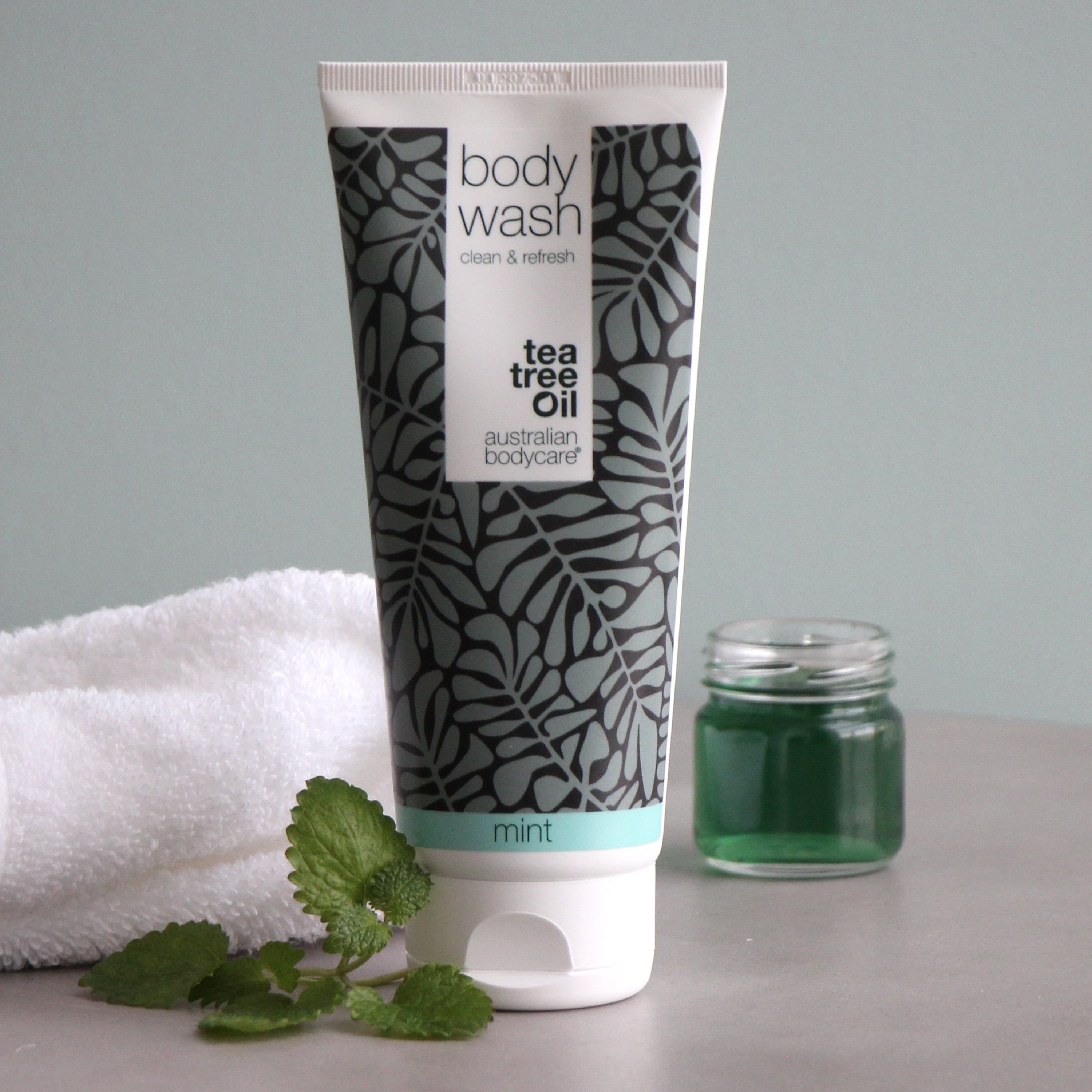 Tubo con scritta "body wash" e "australian bodycare". Accanto, un barattolo con liquido verde.