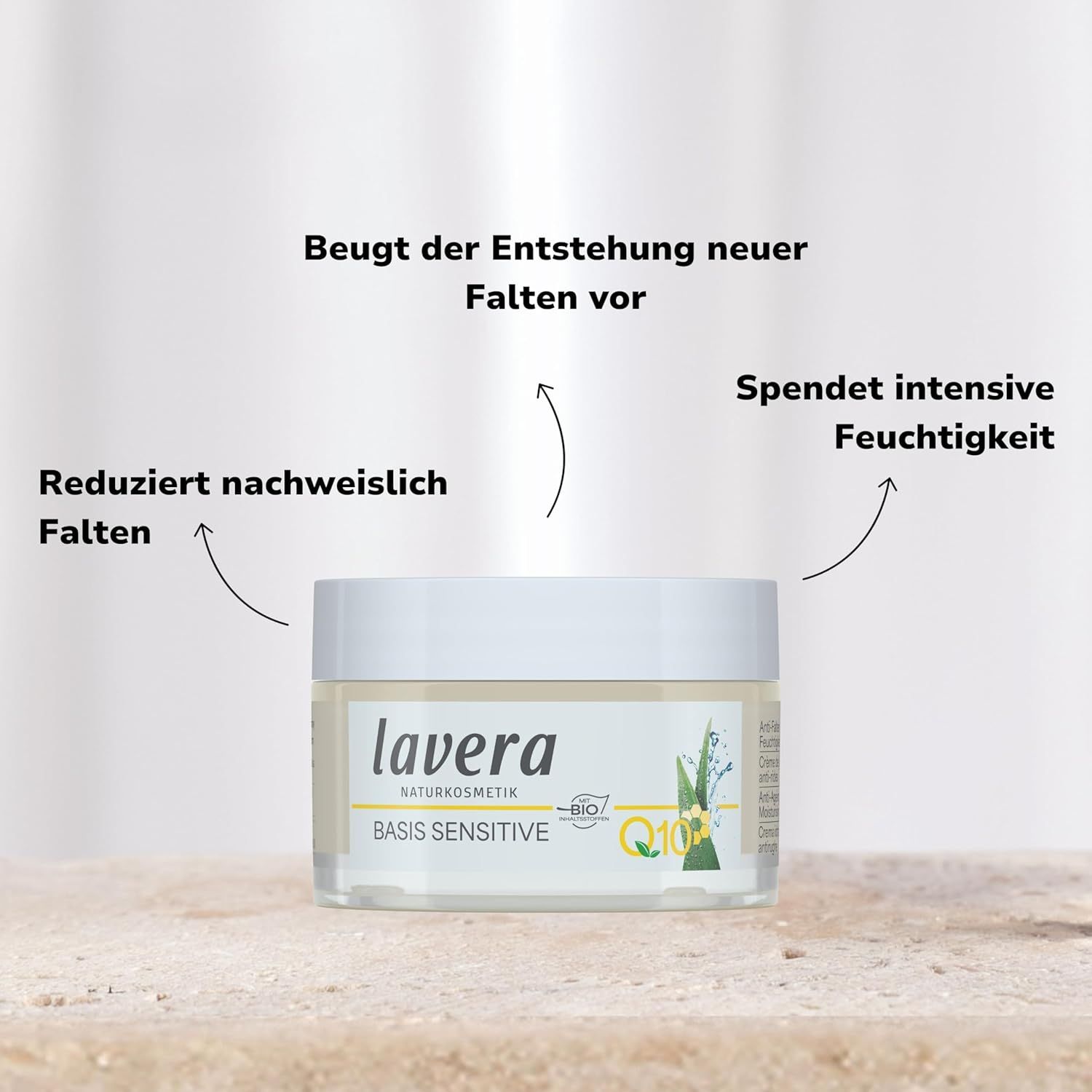 Vasetto di crema con testo: "lavera BASIS SENSITIVE Q10". Frecce indicano il testo su rughe e idratazione.