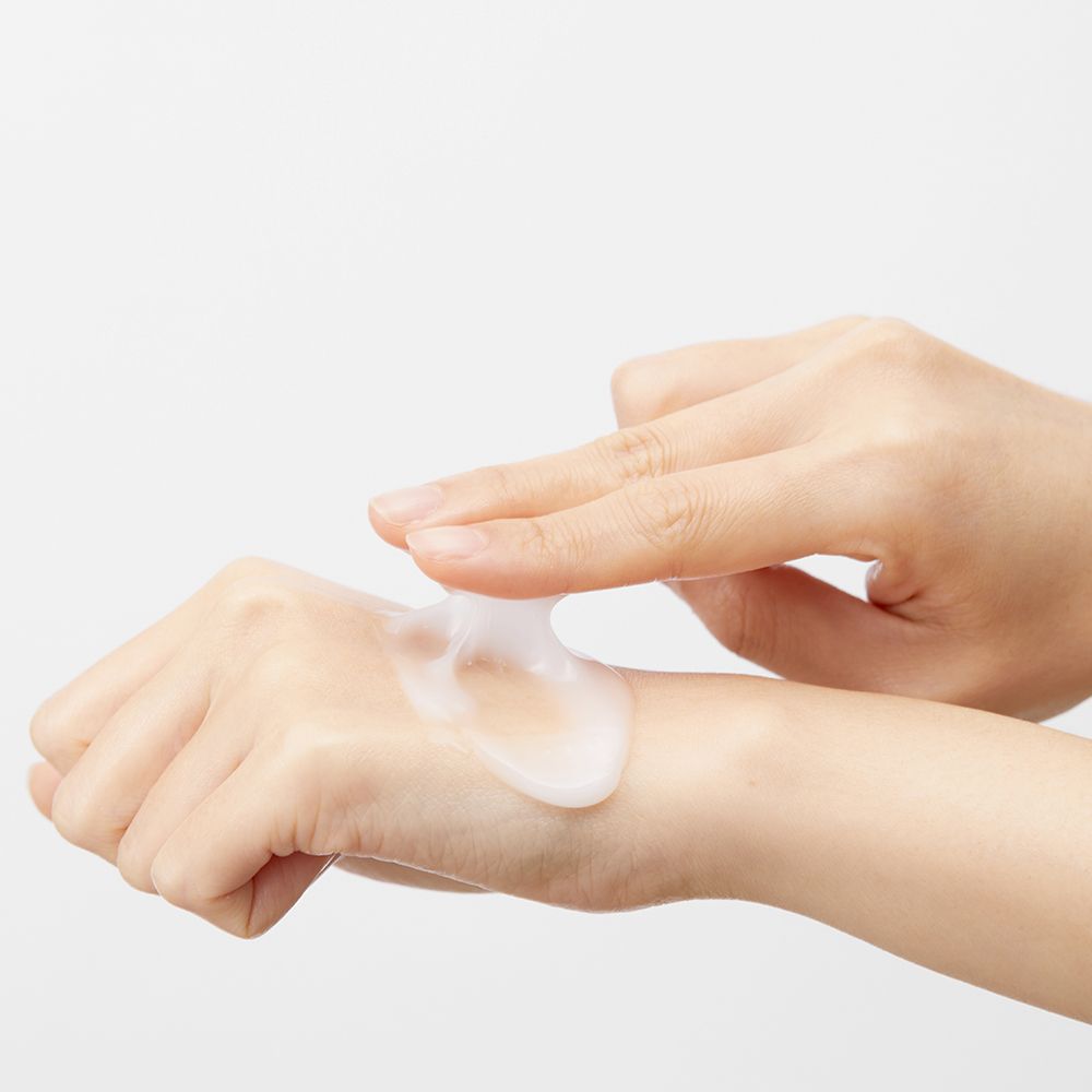 Mani che applicano un liquido trasparente sulla pelle. Sfondo bianco.
