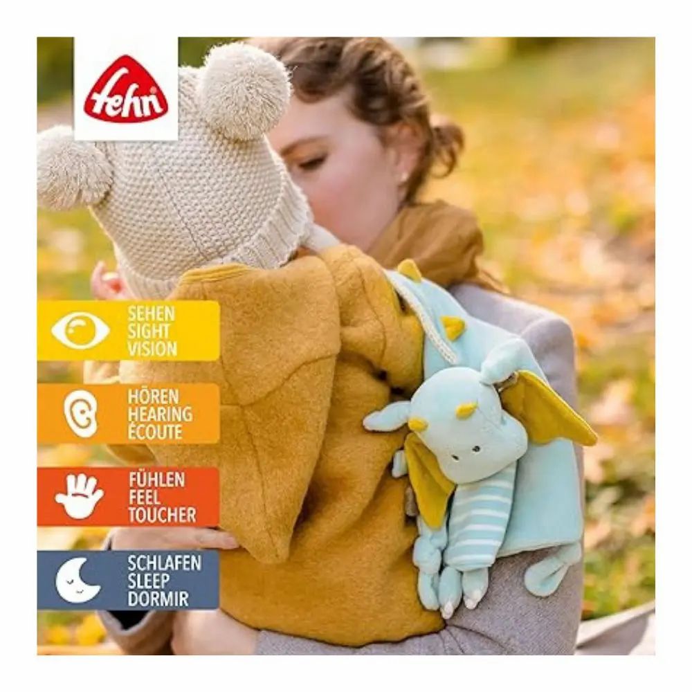 Bambino tenuto da una persona che tiene un peluche a forma di drago blu e giallo. Marchio: fehn. Simboli dei sensi.