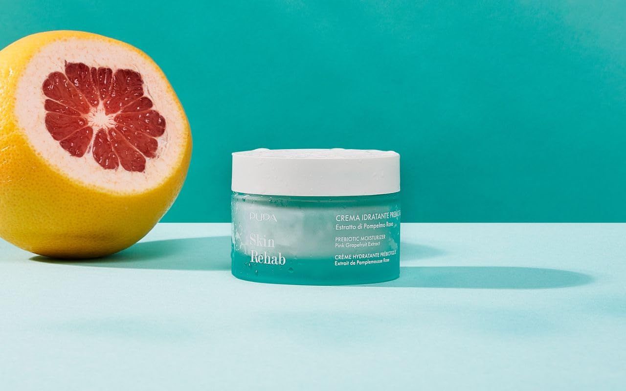 Vasetto turchese con coperchio bianco accanto a pompelmo tagliato. Scritta: Skin Rehab, Crema idratante prebiotica. Marchio: Pupa.