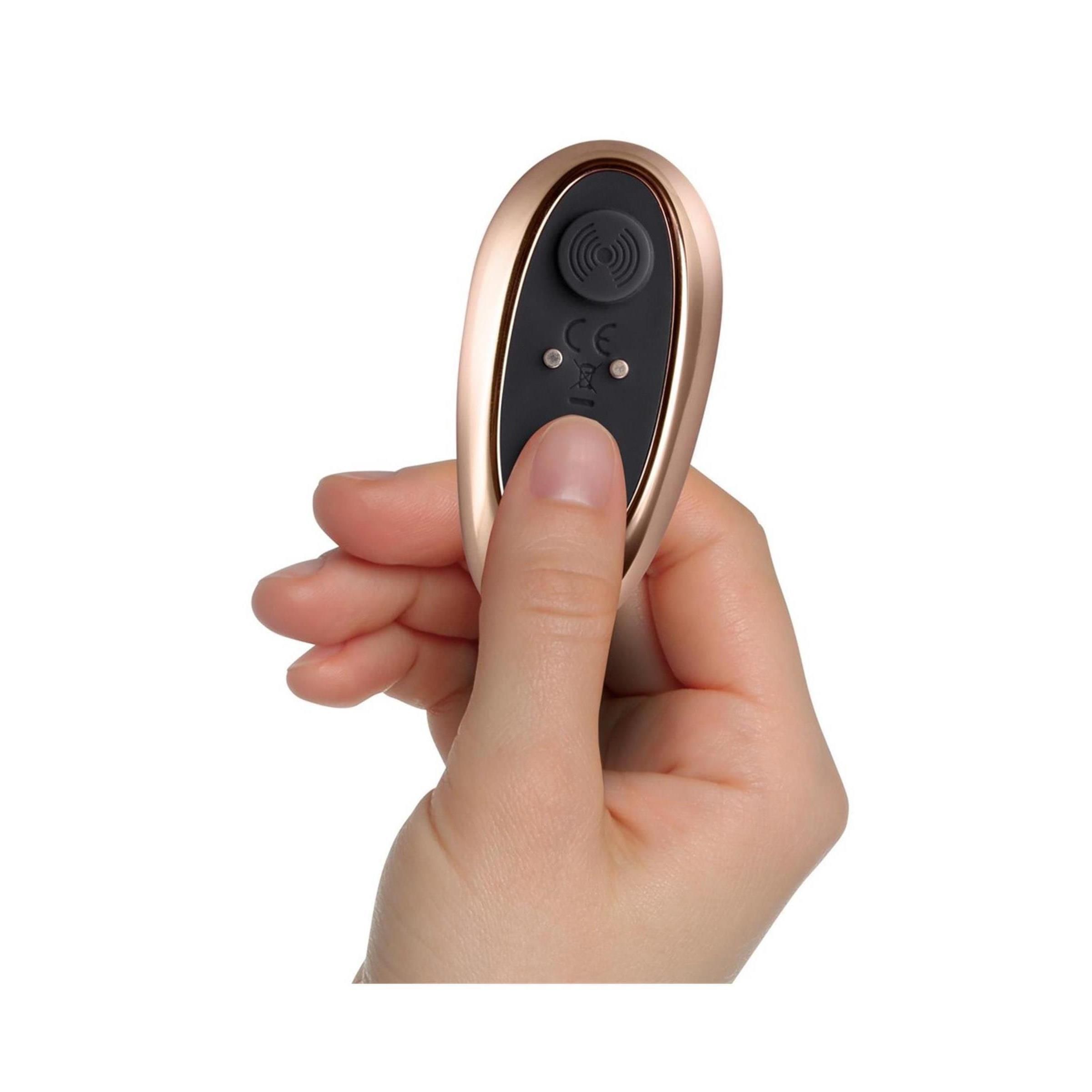 Mano che tiene un telecomando dorato. Telecomando con pulsanti viola. Due pulsanti con simboli.