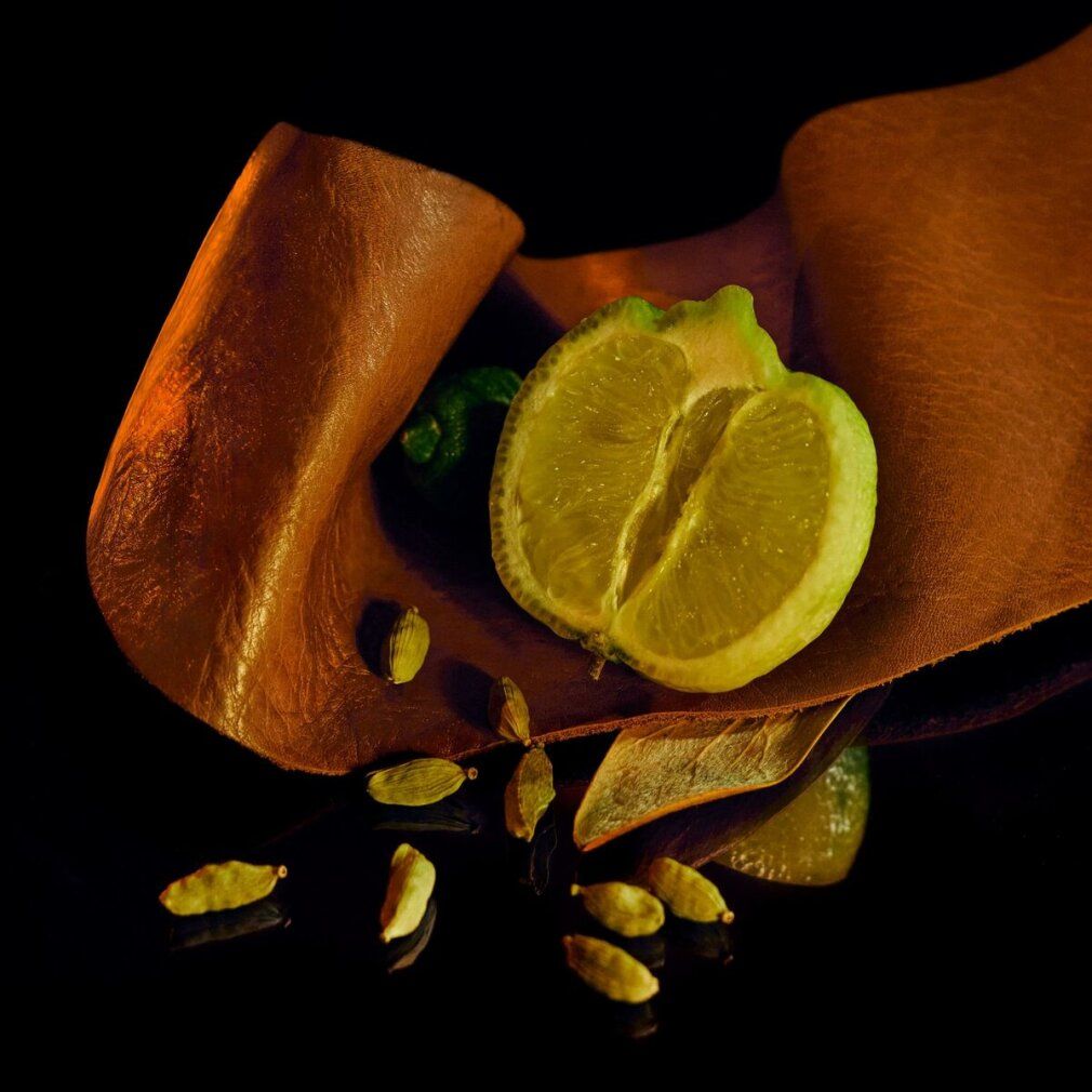 Limone a metà, baccelli di cardamomo e pelle su sfondo nero. Ingredienti naturali per profumo.