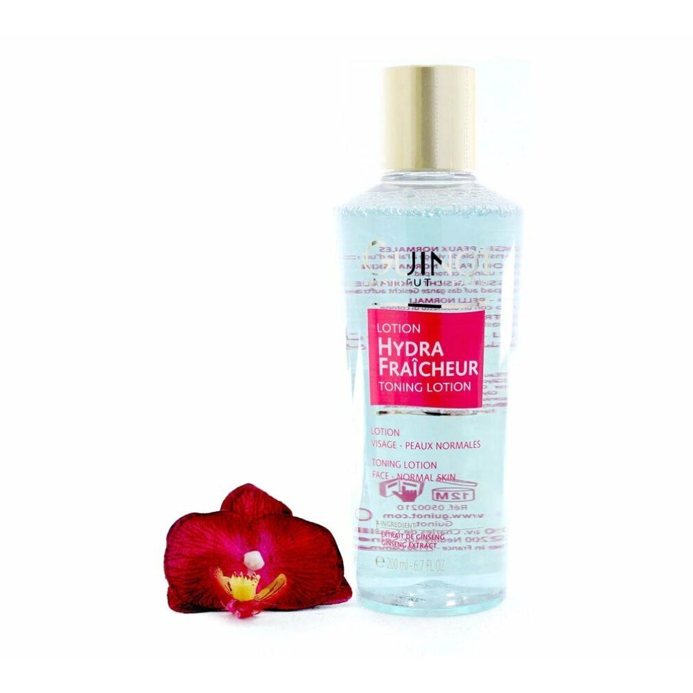 Lozione Hydra Fraicheur Guinot. Flacone con tappo dorato. Etichetta rossa. Orchidea rossa accanto. Liquido trasparente visibile.