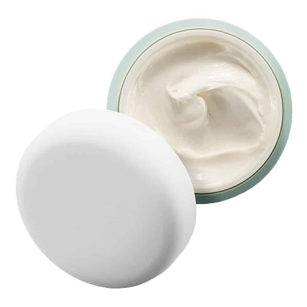 Vaso di crema aperto con coperchio bianco accanto. La crema è bianca e cremosa.