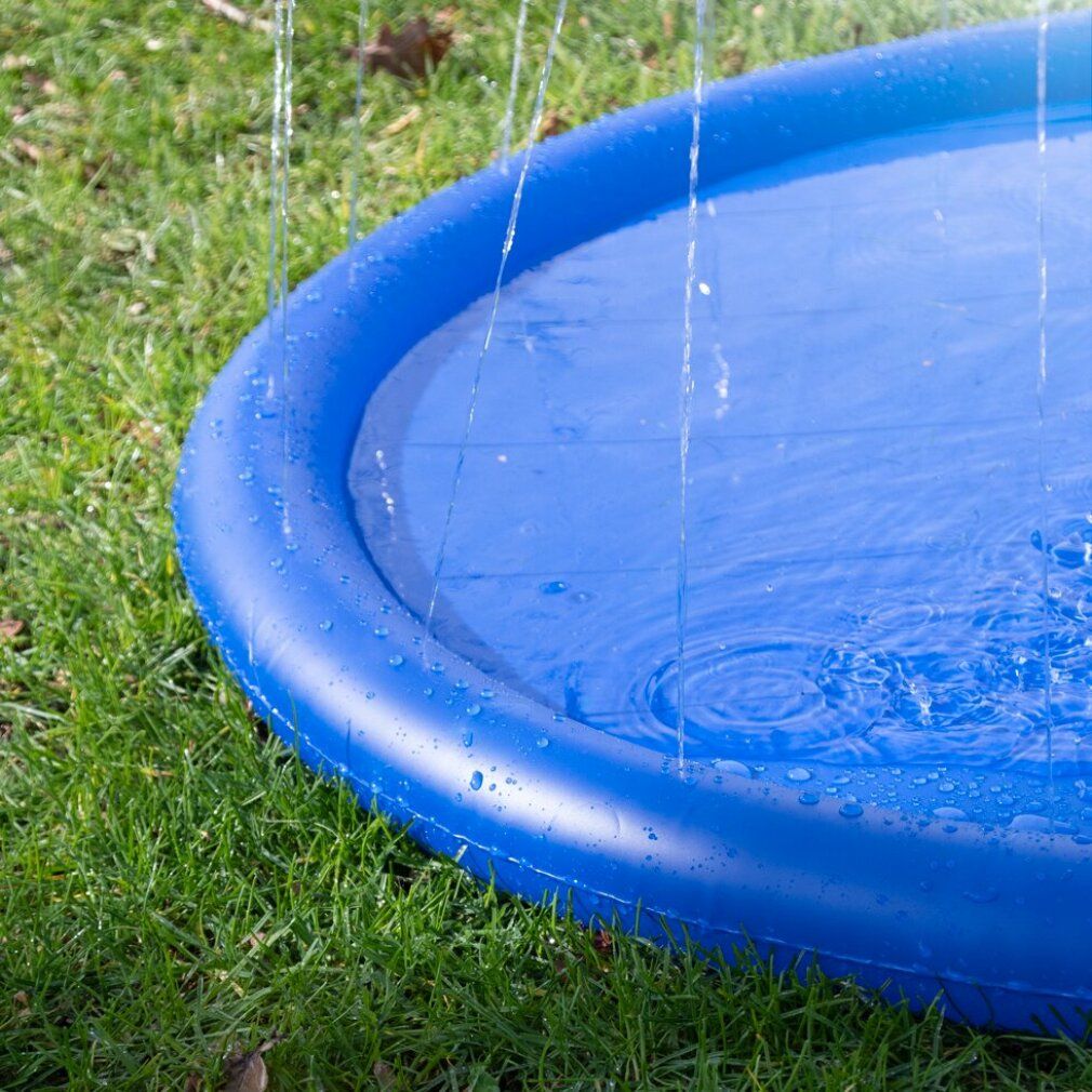 Primo piano di una piscina rotonda blu con getti d'acqua. La piscina è su un prato verde. L'acqua spruzza in aria.