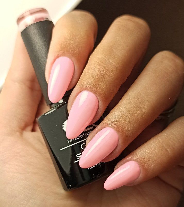 Mano con unghie smaltate e flacone di smalto. Colore rosa. Scritta: LCI, Colore Semipermanente.