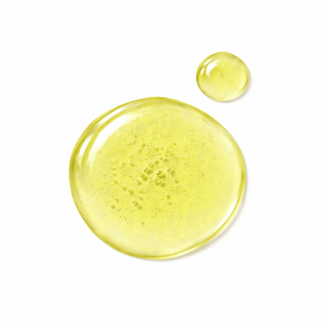 Due gocce di liquido giallo su sfondo bianco. La più grande è rotonda, la più piccola accanto.