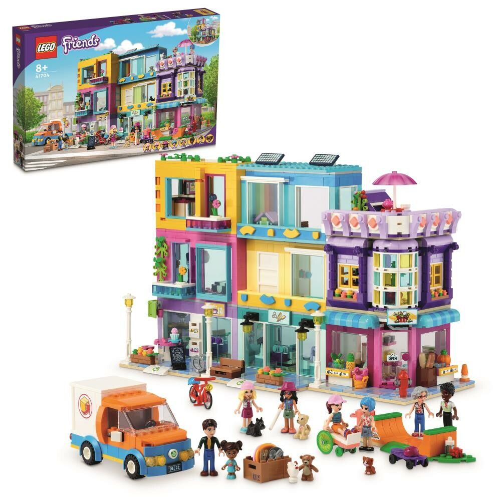 Set di costruzione LEGO Friends Edificio della Strada Principale. La confezione mostra un edificio colorato con negozi e appartamenti. Il set è adatto a bambini dagli 8 anni in su. Include personaggi e accessori. Il set è confezionato in una scatola.
